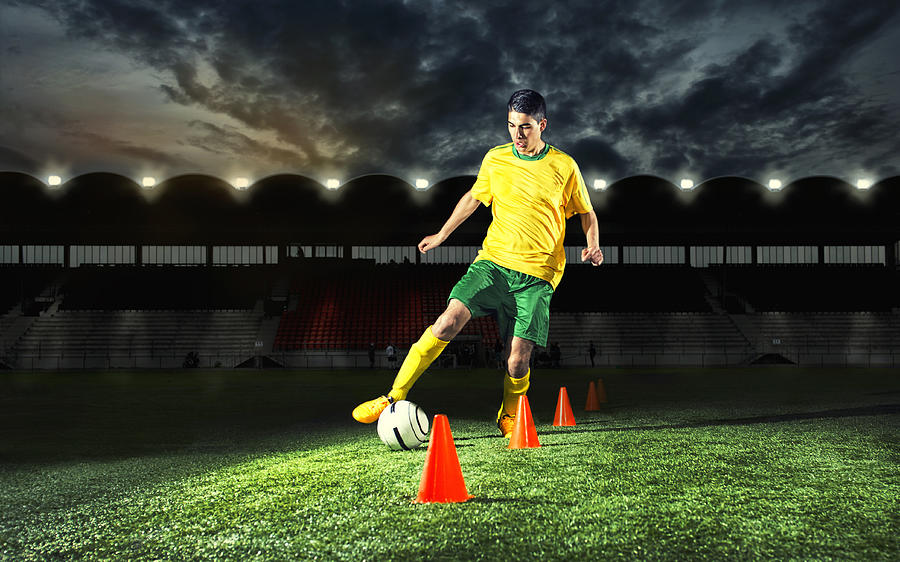 Soccer player is training with plastic cones at night Photograph by Mikkelwilliam