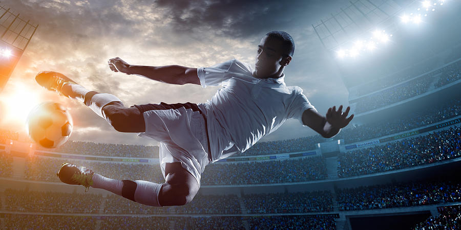 Soccer player kicking ball in stadium Photograph by Aksonov
