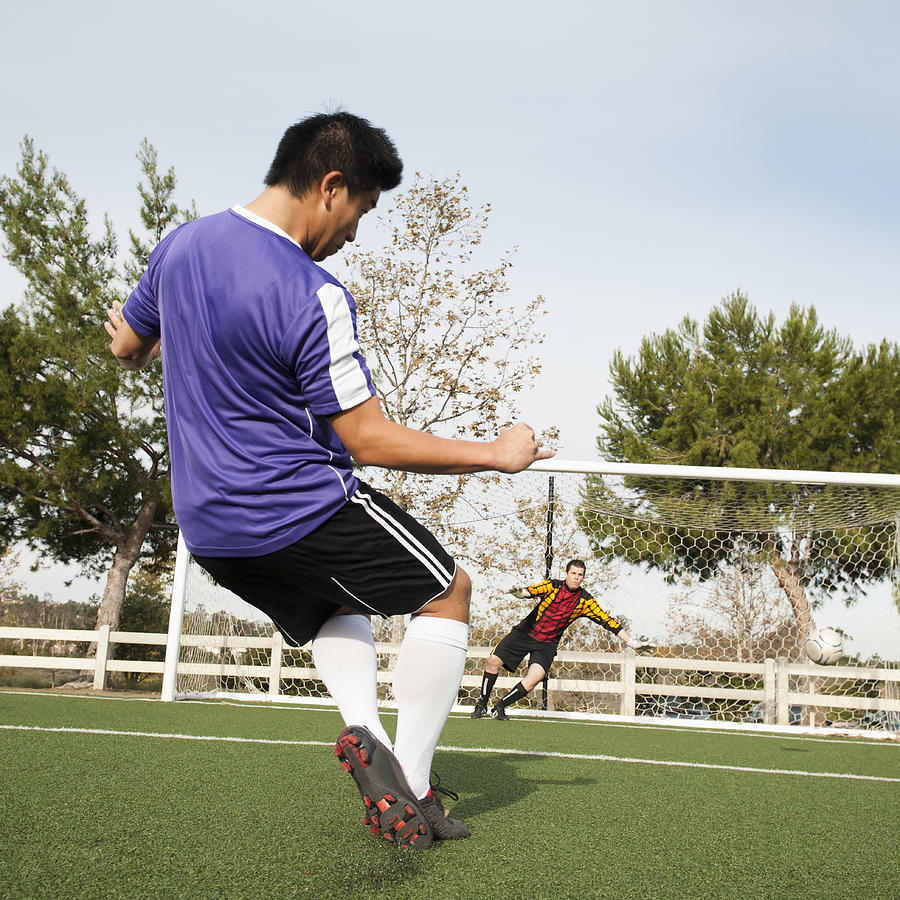 Soccer player kicking ball into goal on soccer field Photograph by Erik Isakson