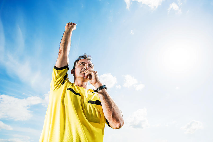 Soccer referee blowing his whistle against the sky. Photograph by Skynesher