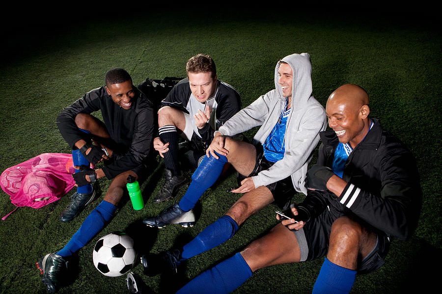 Soccer team resting on pitch after game Photograph by Image Source
