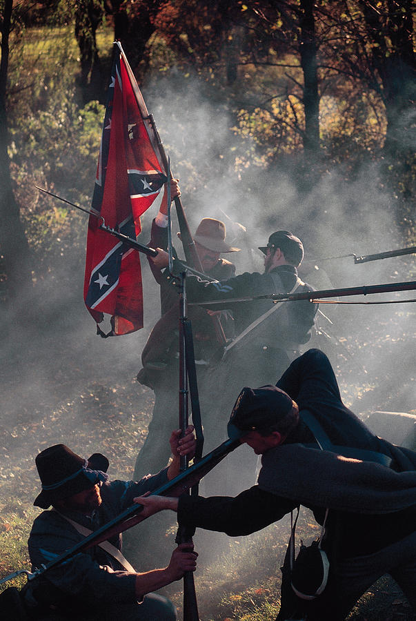 Soldiers raising confederate flag during Civil war reenactment Photograph by Comstock