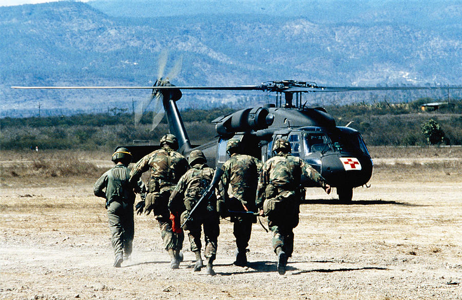 Soldiers running to medical helicopter Photograph by Stocktrek
