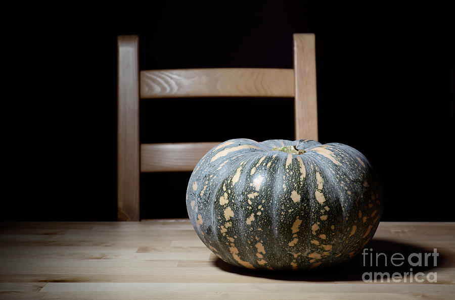 Solitary pumpkin on rustic table with chair. Photograph by Milleflore Images