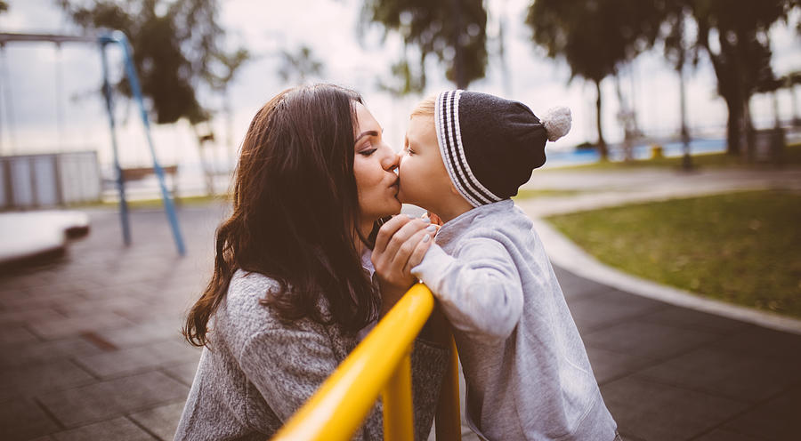 Son giving a kiss to his mother at the playground Photograph by Wundervisuals
