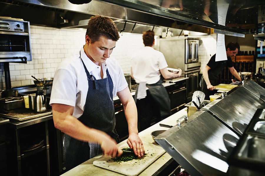 Sous chef chopping cilantro in restaurant kitchen Photograph by Thomas Barwick