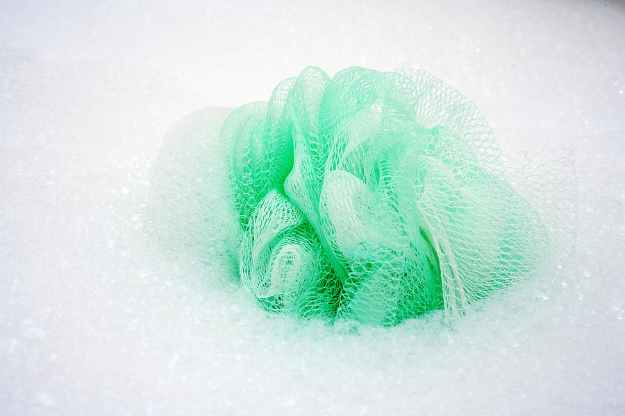Spa elements, Green loofa with lots of bubbles in bathtub. Photograph by Design Pics/Tomas del Amo