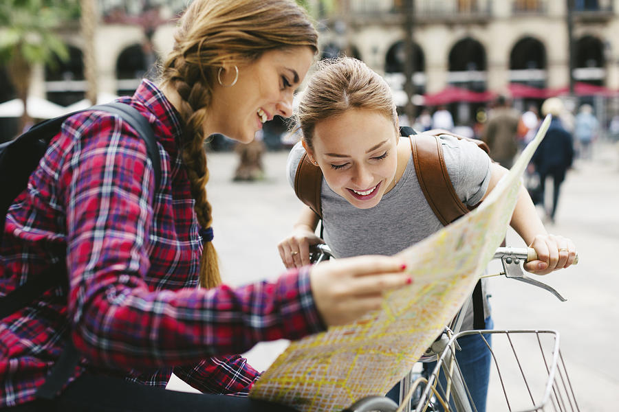 Spain, Barcelona, two young women with map on bicycles in the city Photograph by Westend61