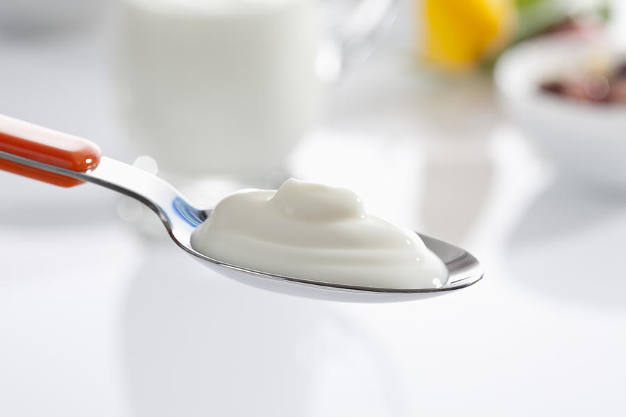 Spoon of yogurt against white background, close up Photograph by Westend61