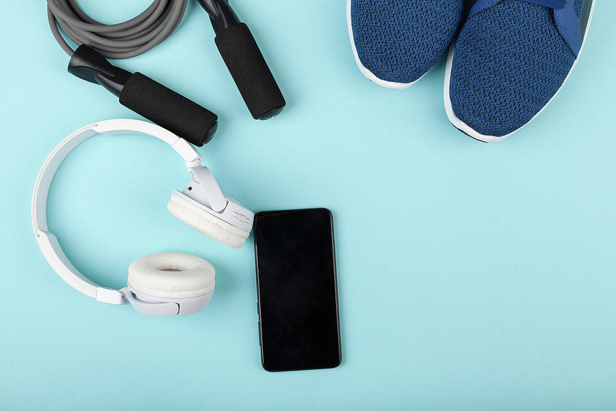 Sport Shoes, Skipping Rope, Mobile Phone With Wireless Headphones On Blue Background. Photograph