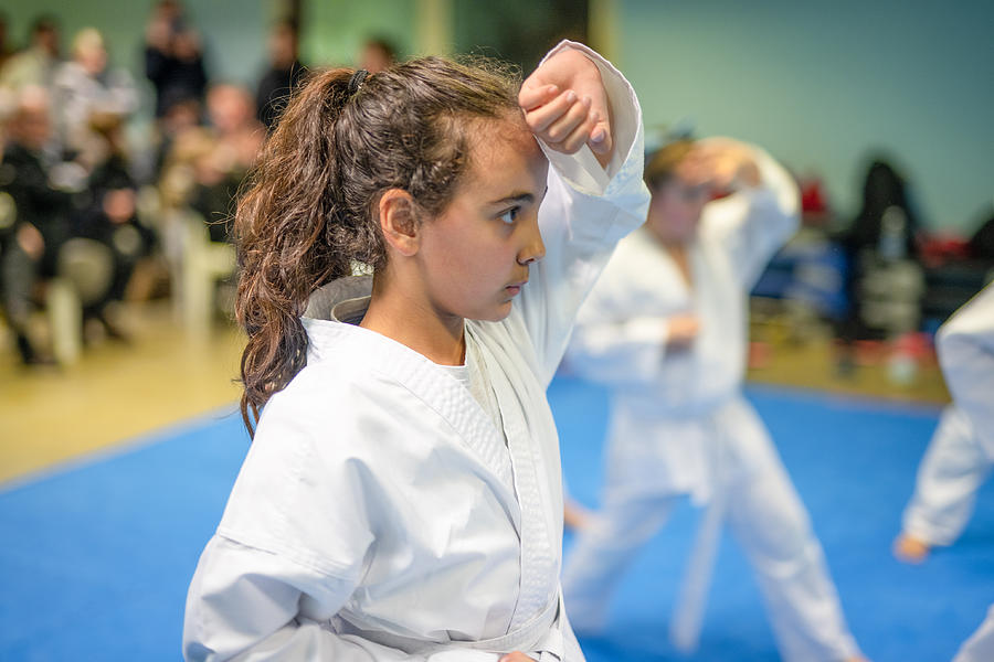 Sports and disciplines. Martial arts. Pre-teen girl during a karate class in gym Photograph by Paola Giannoni