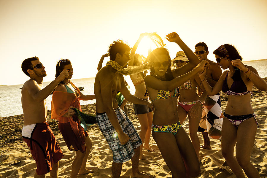 Spring break backlit group of young people dancing on beach Photograph by Apomares