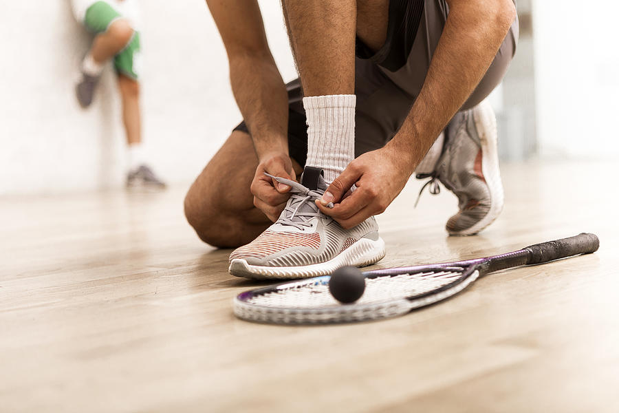 Squash player tying shoelaces Photograph by Nastasic