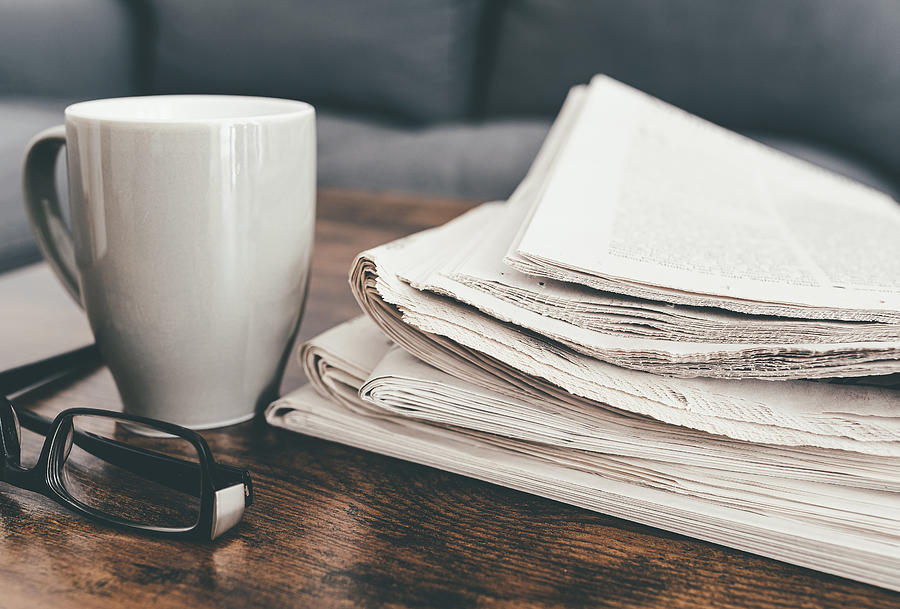 Stack Of Newspapers, Coffee Mug And Glasses On Living Room Table Photograph by Christian Horz