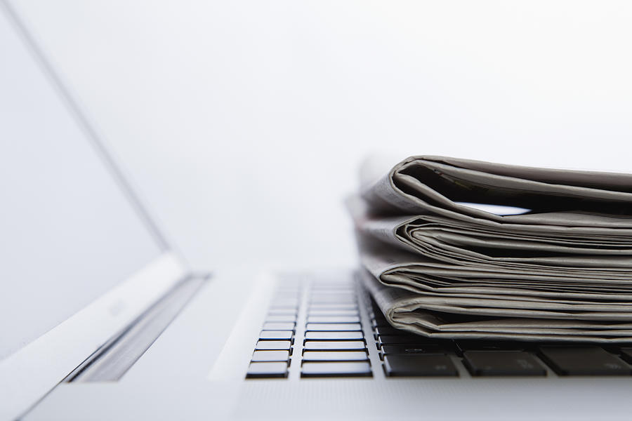 Stack of newspapers on laptop. close-up Photograph by Vstock
