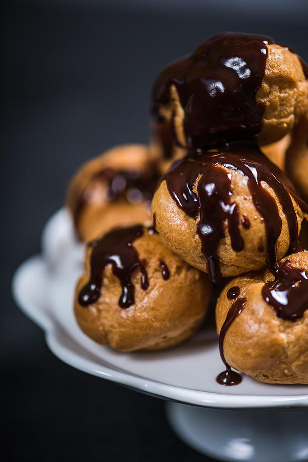 Stack of profiteroles eclairs with dark melted chocolate Photograph by Merc67