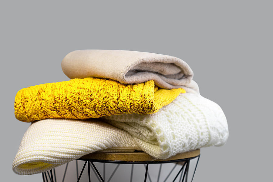 Stack of Trendy Bright illuminating Yellow, Gray and White Woolen Knitted Sweaters. Photograph by Iryna Veklich