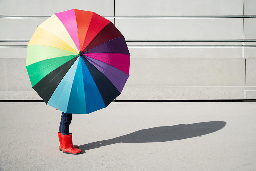 Standing girl with multicolored umbrella in front of a concrete wall Photograph by Kamisoka