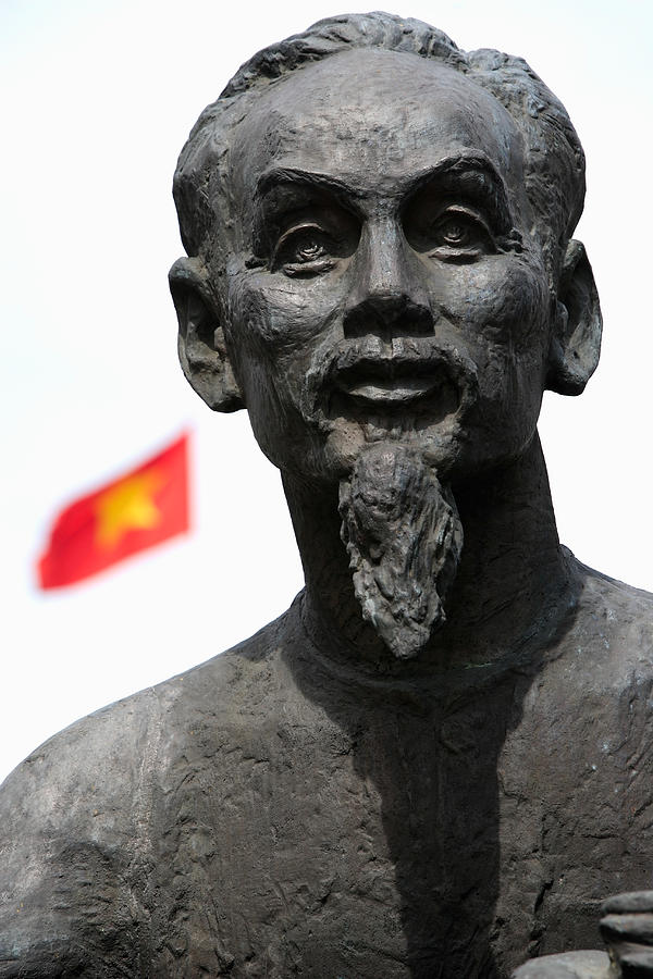 Statue of Ho Chi Minh with Vietnamese flag in background Photograph by Cultura/Oanh