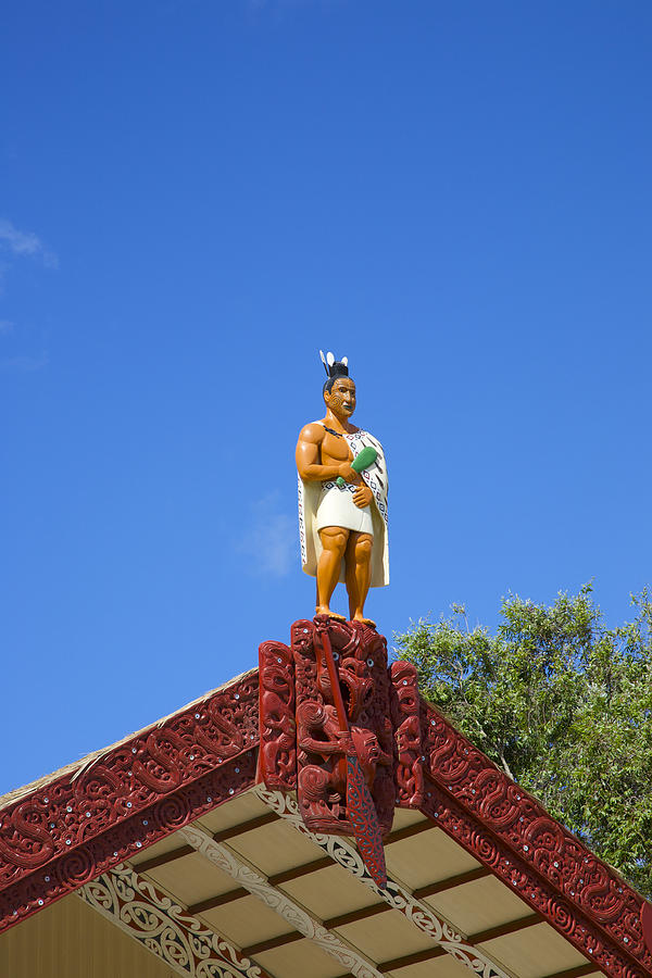 Statue of Maori warrior atop building Photograph by Barry Winiker