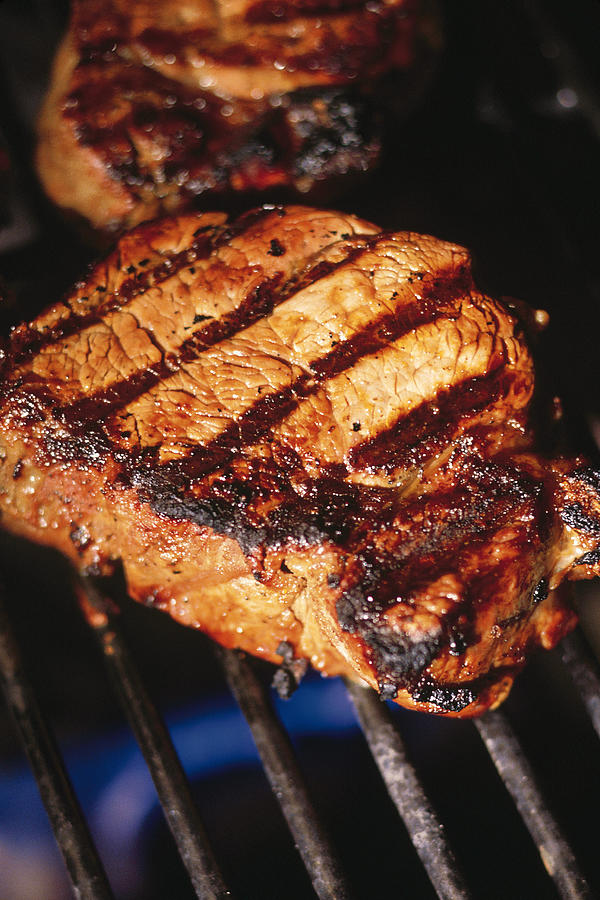 Steaks on grill Photograph by Comstock