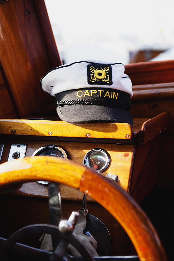 Steering wheel and captains hat in boat Photograph by Johner Images