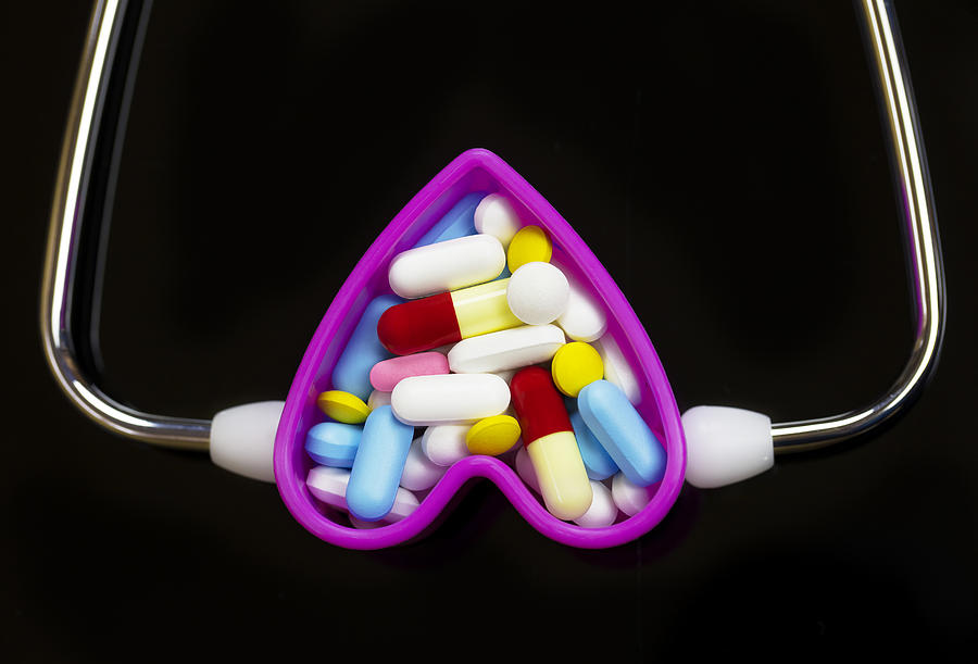 Stethoscope, Capsules and pills in Heart-shaped Container On black background. Medical concept Photograph by Mikroman6