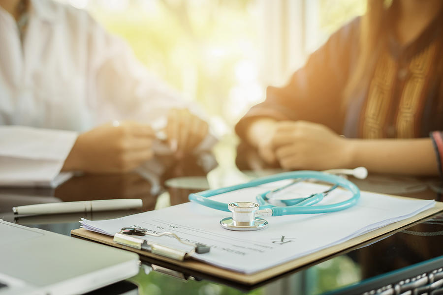 Stethoscope with clipboard and Laptop on desk,Doctor working in hospital writing a prescription, Healthcare and medical concept,test results in background,vintage color,selective focus Photograph by Asawin_Klabma