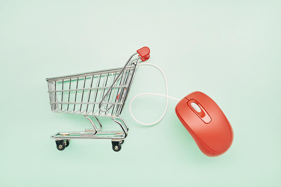 Still life of a small shopping cart and red computer mouse on turquoise background Photograph by The_burtons