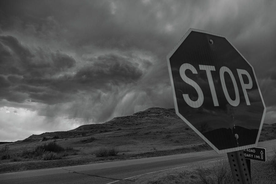 Stop sign and storm clouds at Theodore Roosevelt National Park in North Dakota in black and white Photograph by Eldon McGraw