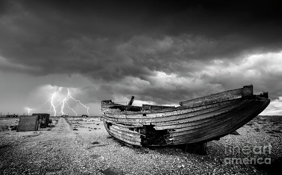 Stormy Dungeness, Wrecked boat on a shingle beach with lightning Photograph by Neale And Judith Clark