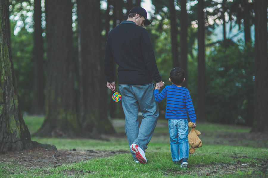 Stranger walking in a public park holding little boys hand Photograph by FatCamera