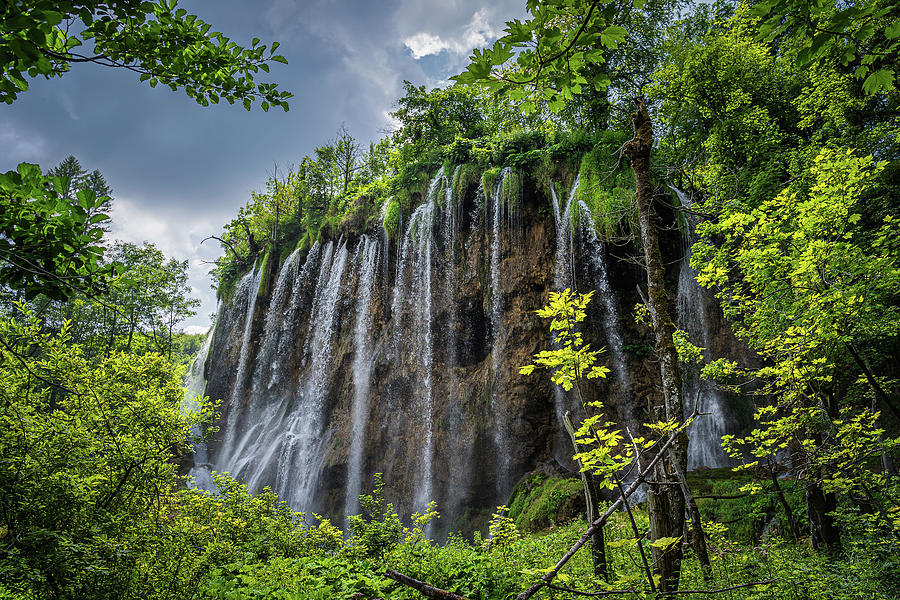 Streaks of water from waterfall framed by branches in Plitvice Lakes ...