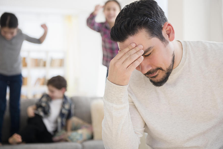 Stressed Caucasian father with shouting children in living room Photograph by JGI/Jamie Grill