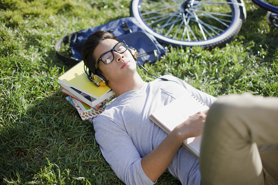 Student listening to headphones in grass Photograph by Paul Bradbury