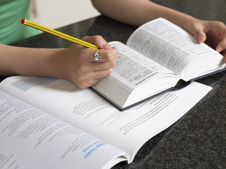 Student with dictionary and textbook Photograph by Image Source