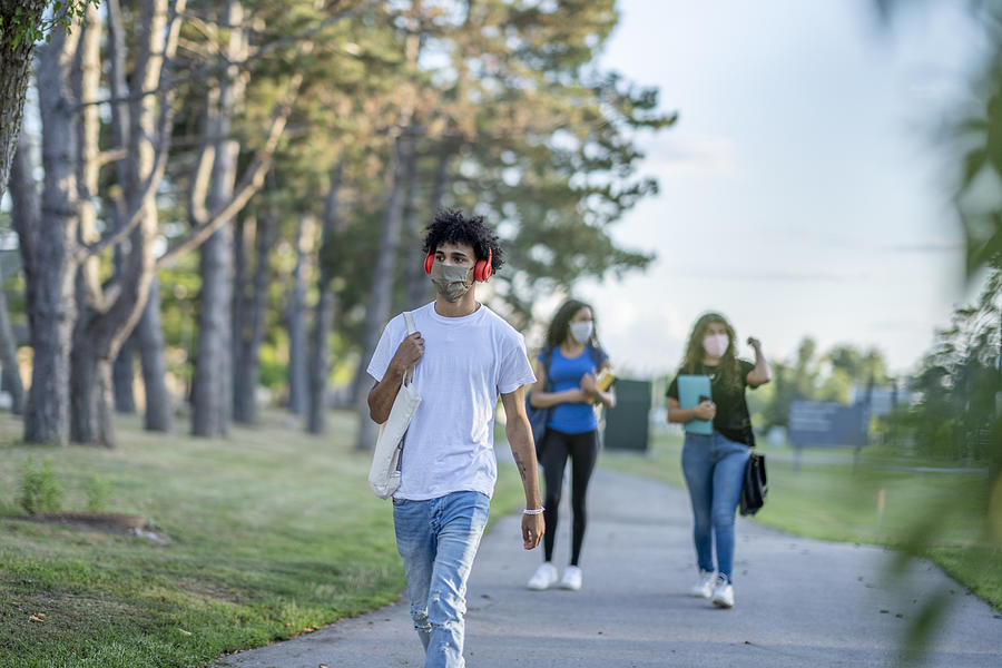 Students walking on school property while wearing masks Photograph by FatCamera