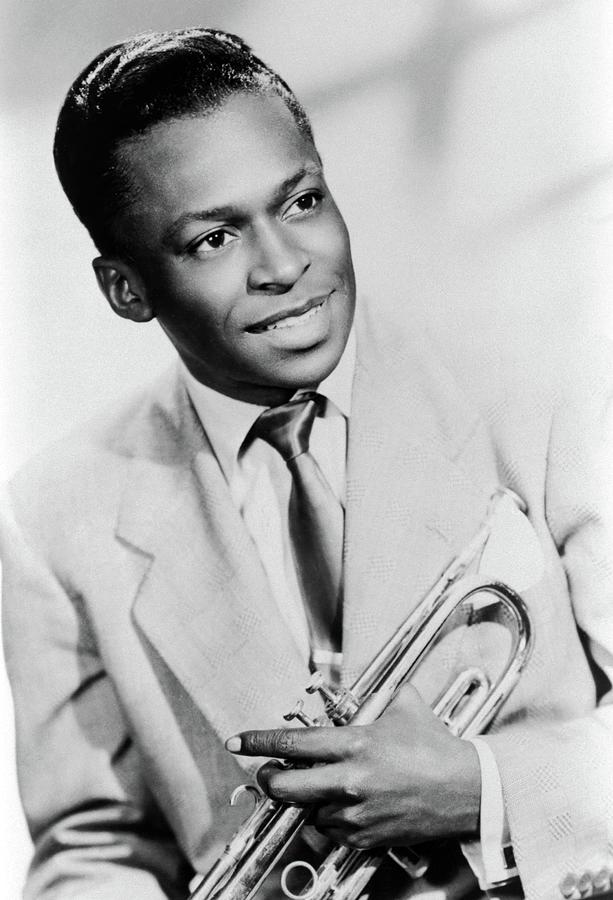 Studio portrait of American jazz trumpeter Miles Davis smiling and holding his trumpet, 1949. Photograph by Album