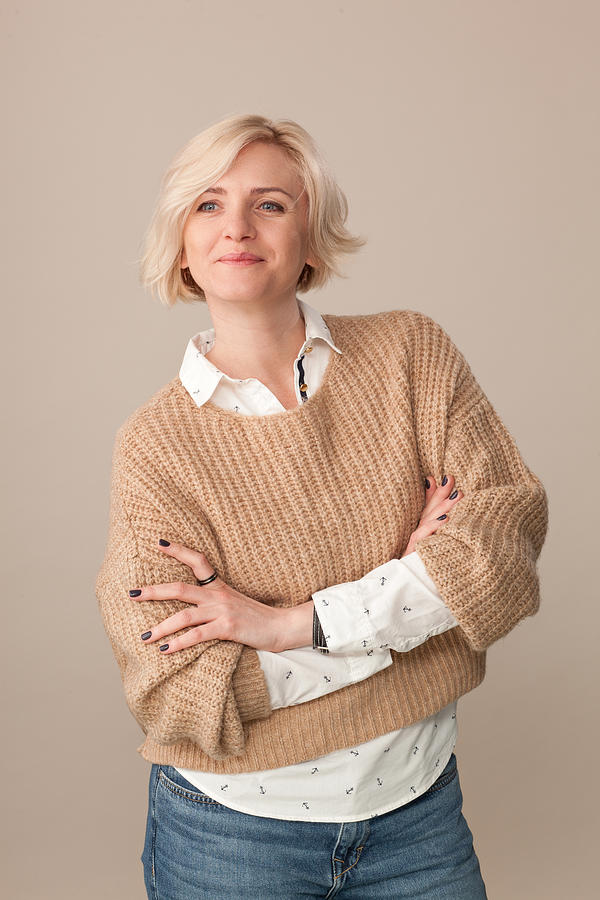 Studio portrait of an attractive 40 year old blonde woman in a beige sweater on a beige background Photograph by Brusinski
