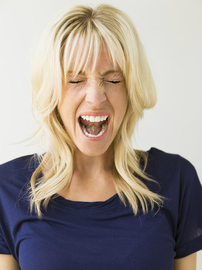 Studio portrait of blonde woman screaming Photograph by Jessica Peterson