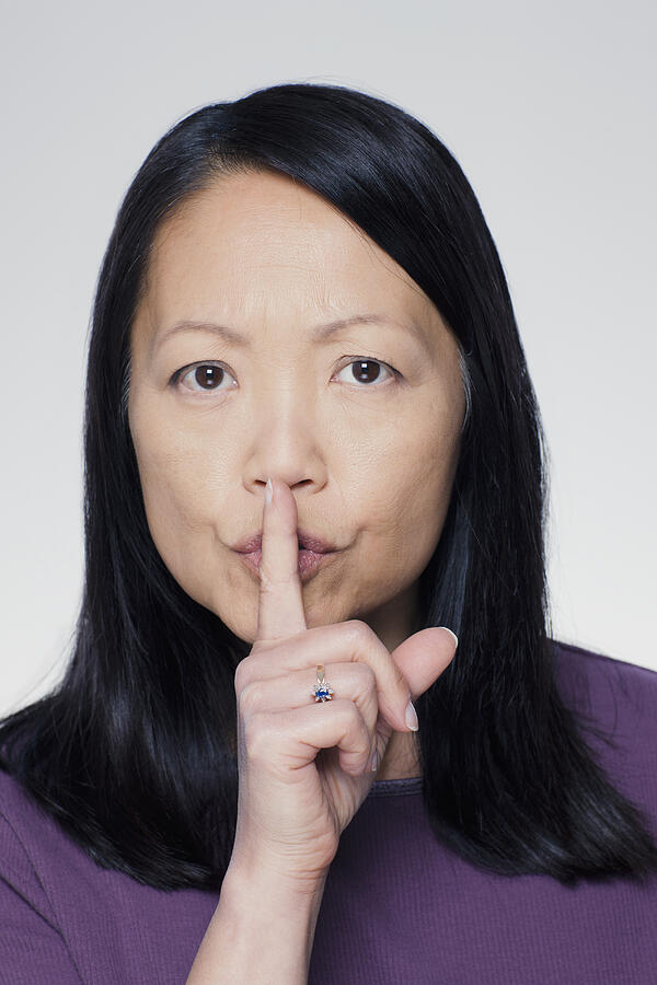 Studio portrait of mature woman with finger on lips Photograph by Rob Lewine