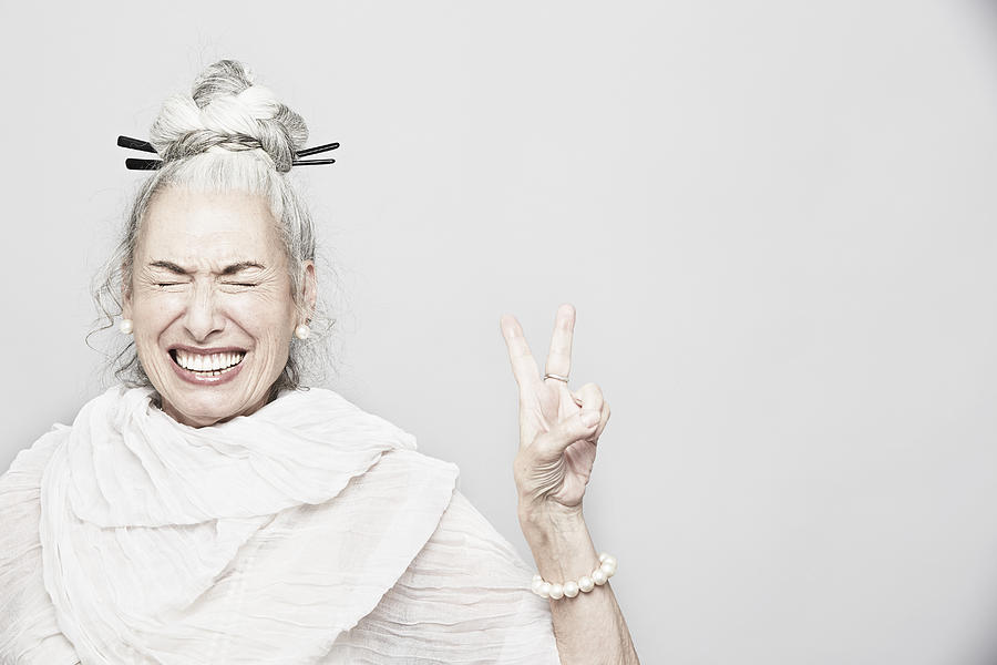 Studio portrait of sophisticated senior woman making victory sign Photograph by Jpm