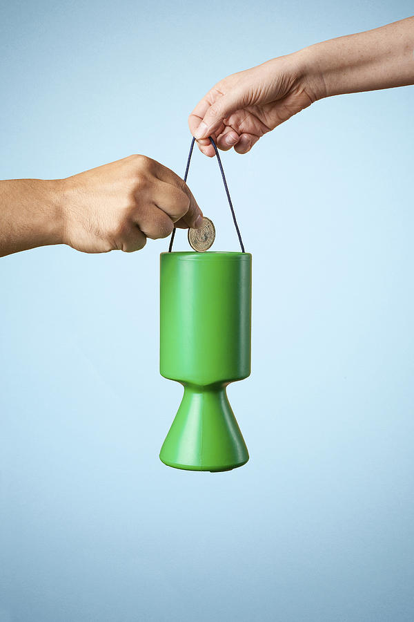 Studio shot of hand putting coin into charity collection box Photograph by Sverre Haugland
