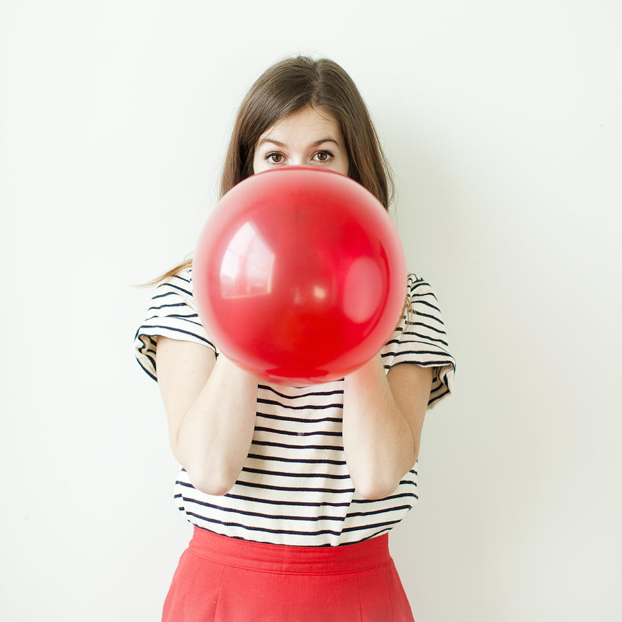 Studio shot of young woman blowing balloon Photograph by Tetra Images - Jessica Peterson