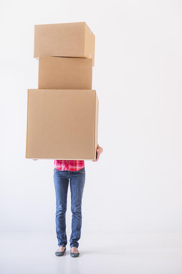 Studio shot of young woman carrying stack of boxes Photograph by Daniel Grill