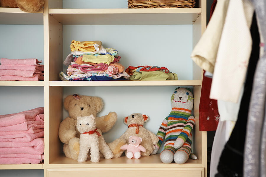 Stuffed animals, clothing and towels on shelves in closet Photograph by Thomas Northcut