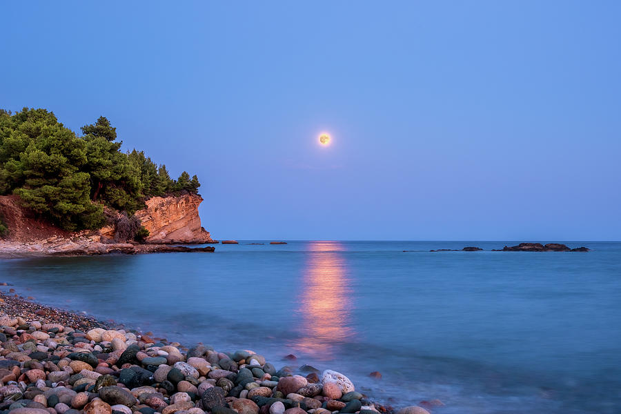 Sturgeon Full Moon Rising Over a Rocky Beach Photograph by Alexios Ntounas