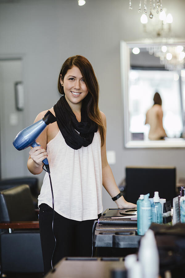 Stylist holding blow dryer in salon Photograph by Take A Pix Media