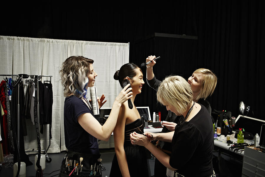 Stylists and model backstage at fashion show Photograph by Thomas Barwick
