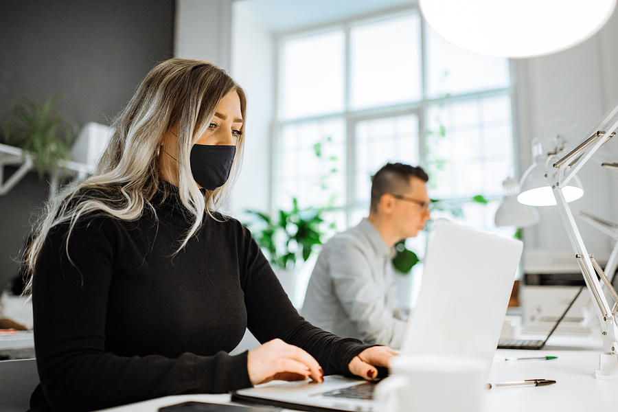 Successful entrepreneurs working in the office with face masks, keeping social distance Photograph by Drazen_